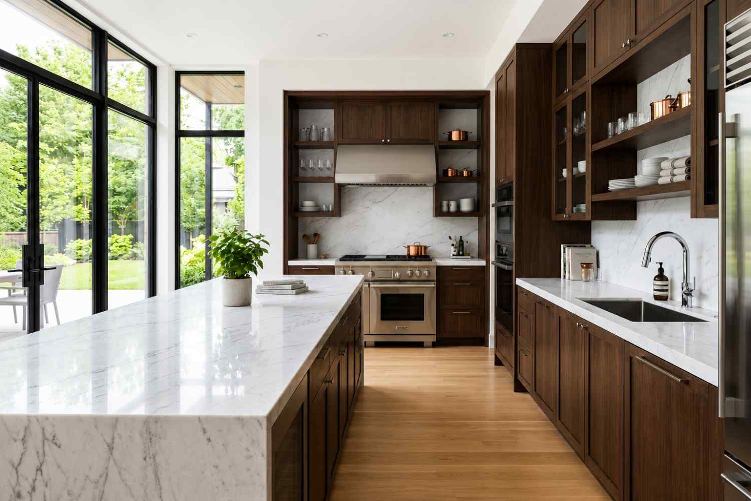 Modern luxury kitchen with a white marble waterfall island, custom walnut cabinetry, stainless steel appliances, open shelving, and floor-to-ceiling windows. Bright contemporary kitchen design featuring premium finishes, natural light, and seamless indoor-outdoor living in a high-end custom home.