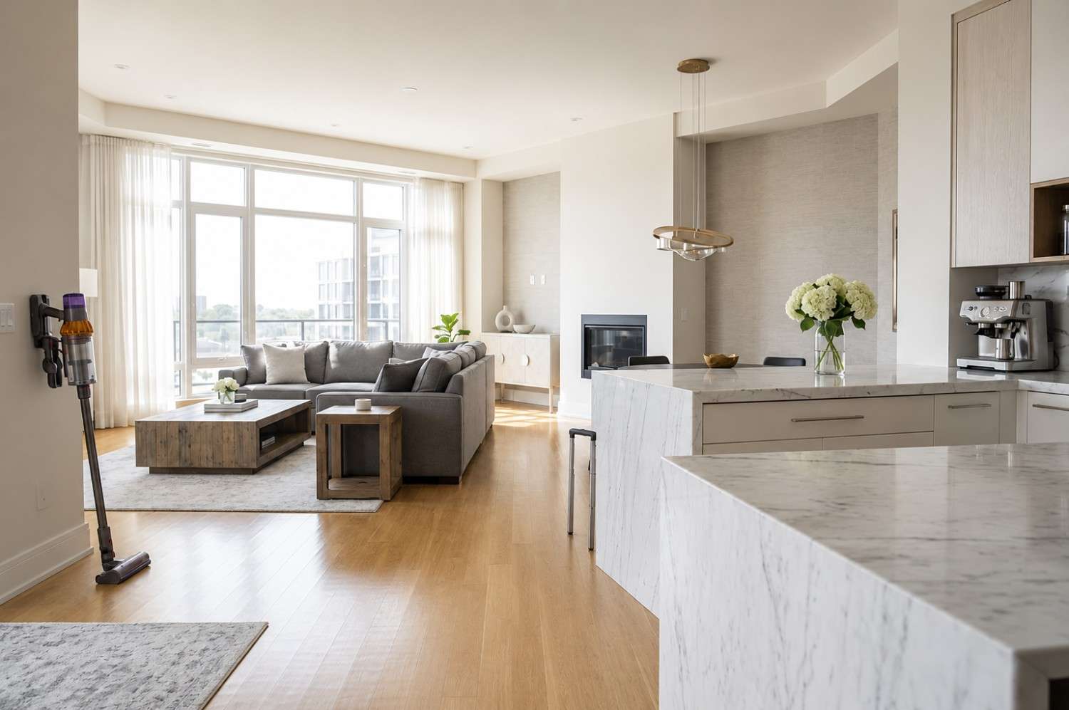Professional house cleaning service in a modern luxury apartment featuring a marble kitchen island, hardwood floors, large windows, and contemporary furnishings. Vacuum cleaner and cleaning caddy showcase residential deep cleaning, maid services, home maintenance, and premium housekeeping in an upscale living space.
