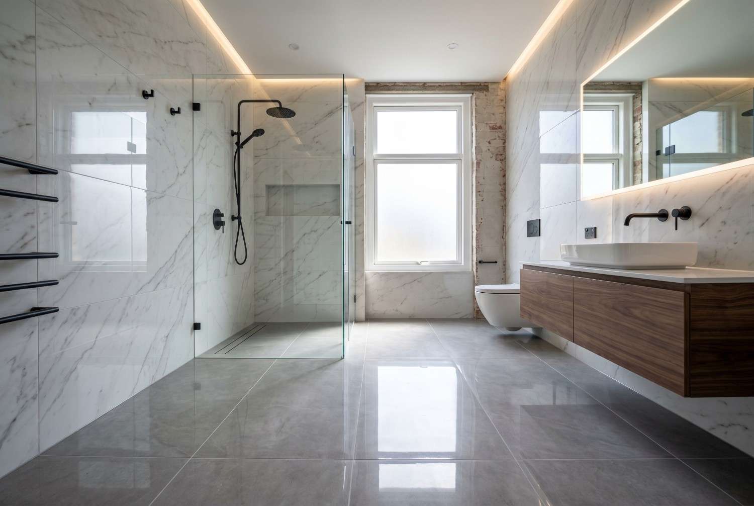 Modern luxury bathroom with walk-in glass shower, floating wood vanity, marble wall tiles, and illuminated mirror. Contemporary spa-inspired bathroom design featuring premium fixtures, large-format flooring, minimalist aesthetics, natural light, and high-end residential remodeling.