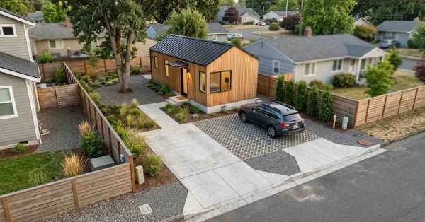 Detached ADU with an integrated off-street parking space, driveway, pedestrian path, landscaped screening, drainage-conscious paving, and efficient small-lot site layout.